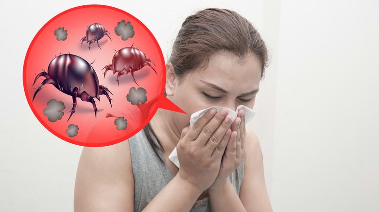 Woman sneezing into a tissue with a thought bubble overhead with image of dust mites and dust clouds