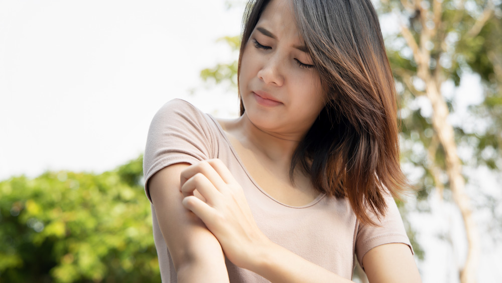 Woman scratching her arm while outside