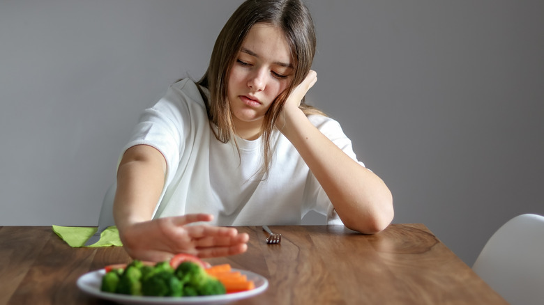 Woman pushing away plate of vegetables