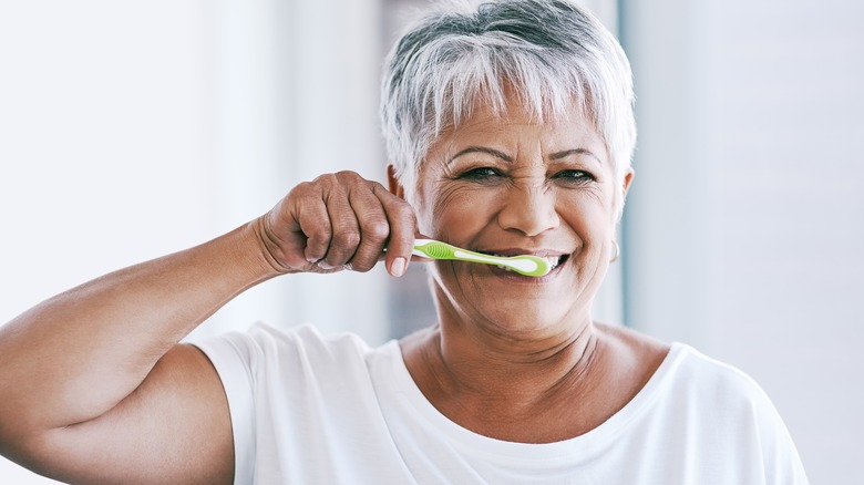 Older smiling woman brushing teeth