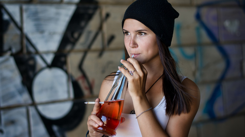 Young girl drinking soda and smoking a cigarette