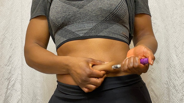 Person injecting insulin into abdomen