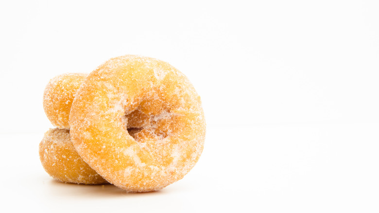 3 miniature sugar donuts with an all white background 