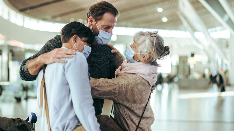 Masked family hugging at airport