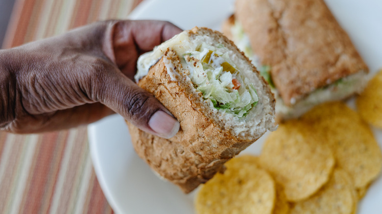 woman's hand holding tuna fish sandwich