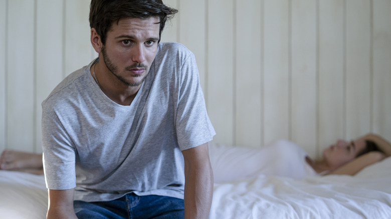 A concerned man sitting on the edge of the bed