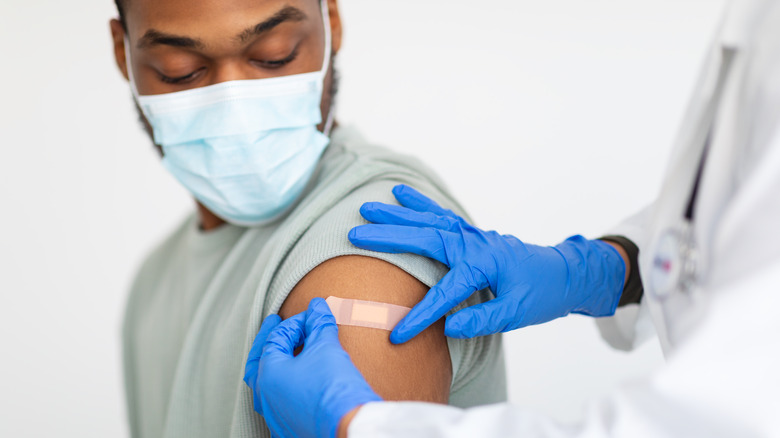 Doctor placing bandaid on patient's arm