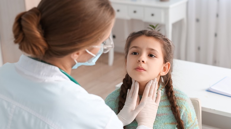 doctor examining a sick girl's neck