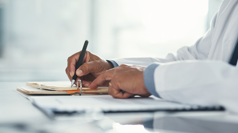 doctor writing on a pad of paper