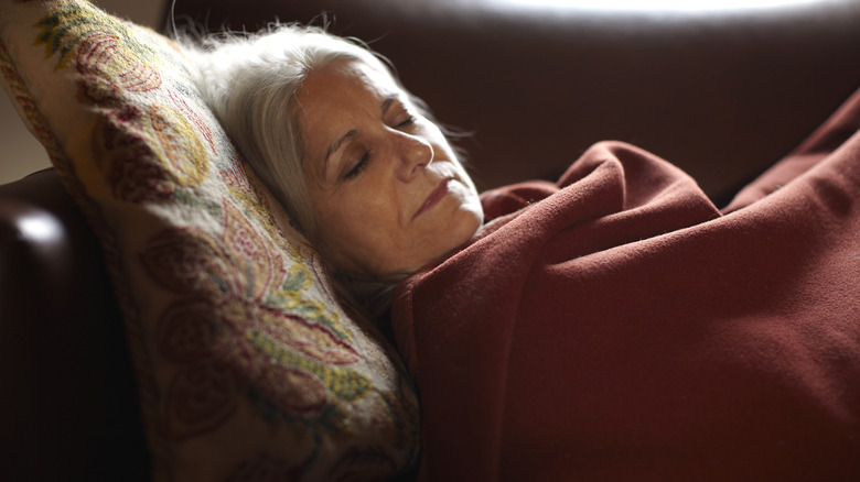 older adult sleeping in bed with heavy blanket