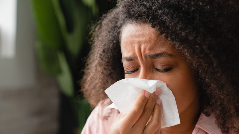 Sick woman blowing nose