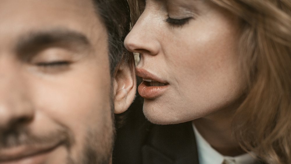 woman whispering in man's ear