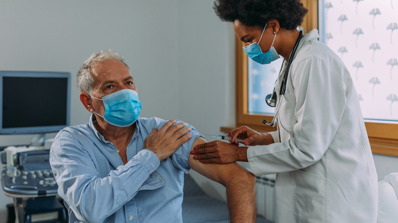 Older masked man receiving vaccine