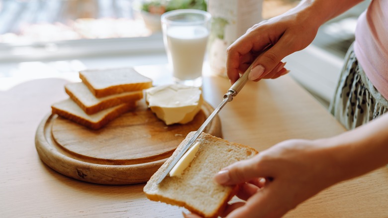 woman's hands buttering a slice of bread