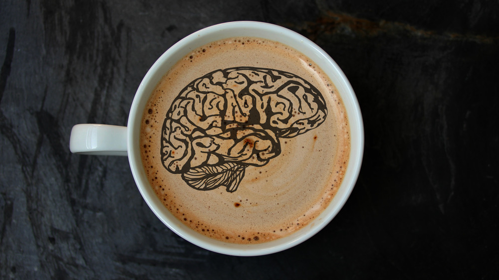 Cup of coffee with black outline of brain drawn on the coffee