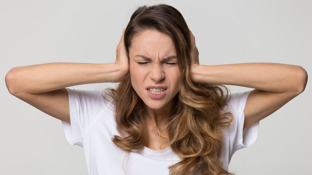 Woman covering her ears with a pained expression