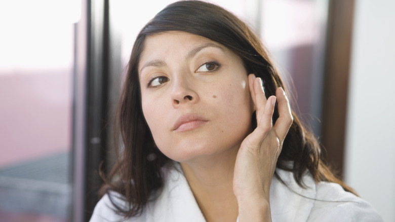 A woman revealing her mole on her cheek