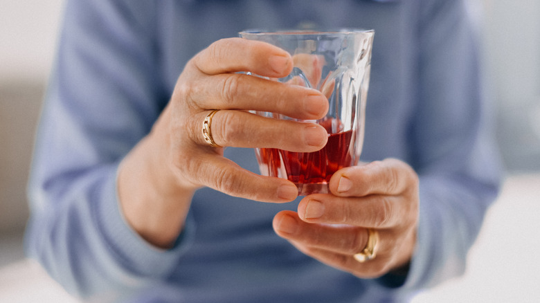 hands holding cranberry juice