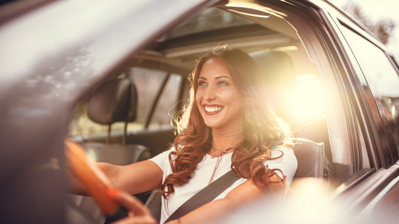 Woman driving in car smiling in sunlight