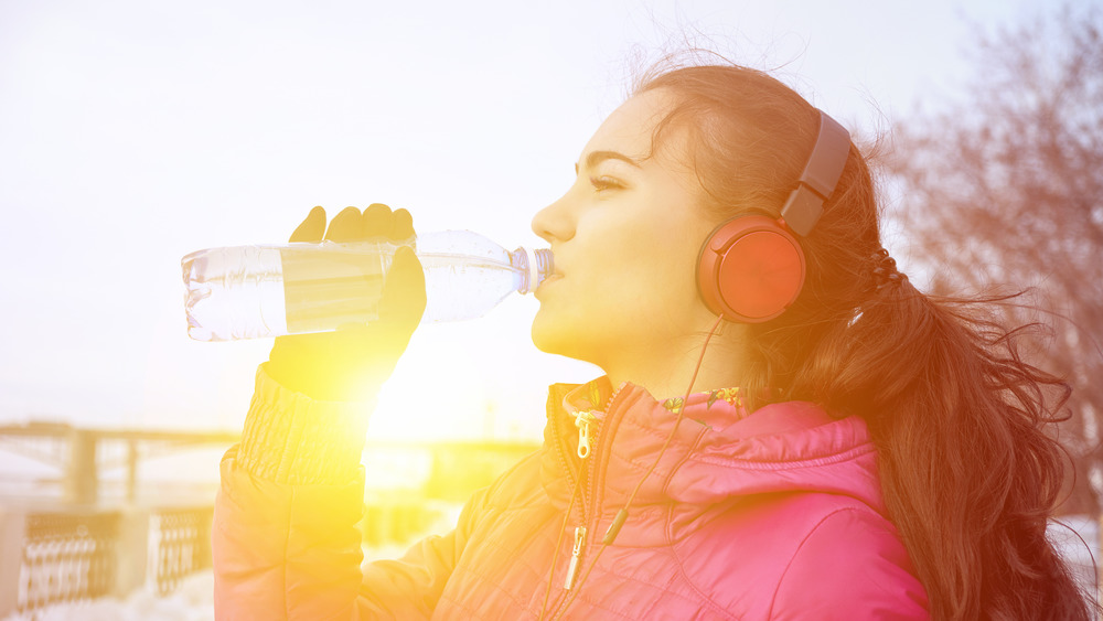 Woman in winter clothes drinking water