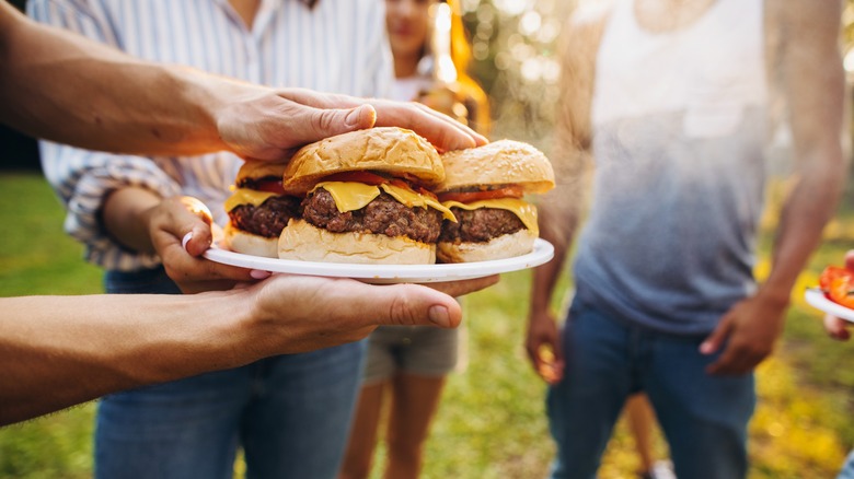 Handing out plate of burgers at barbecue