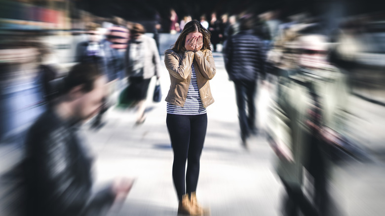 woman stands still as people race past