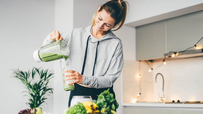 woman pouring a healthy green smoothie