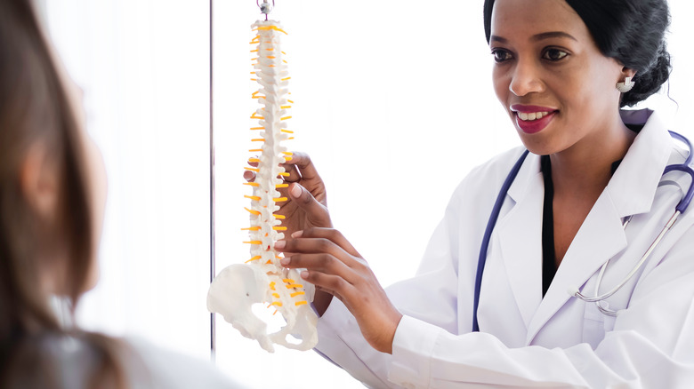 Doctor talking to patient with spine replica