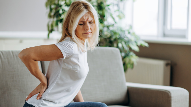 Woman with back pain sitting on sofa
