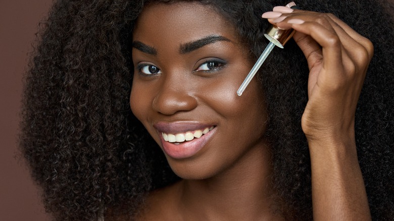 woman applies oil dropper to skin