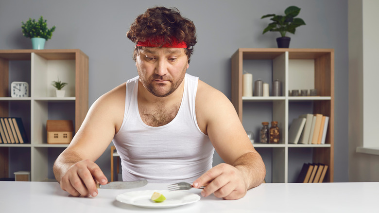 man looking at a tiny portion on his plate 