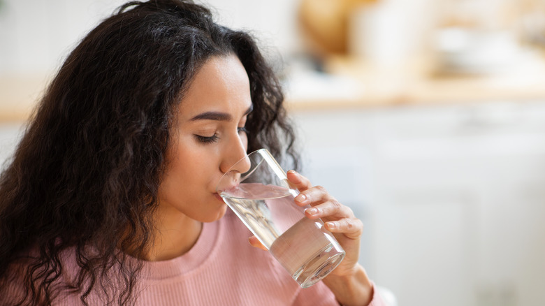 brunette woman drinking water from a glass