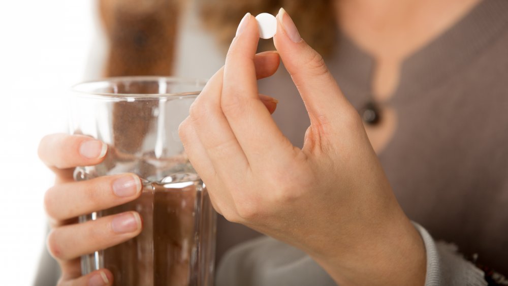 Woman holding aspirin and water