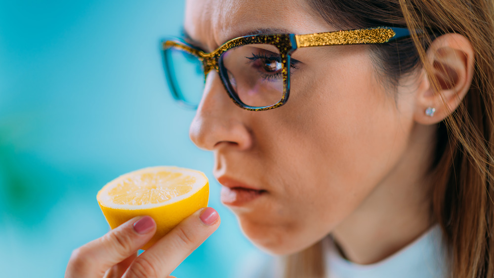 Woman with glasses smelling lemon 