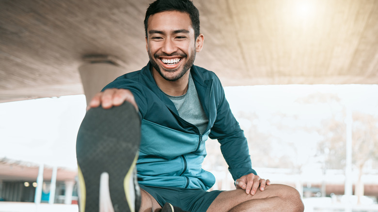 Smiling man doing leg stretches