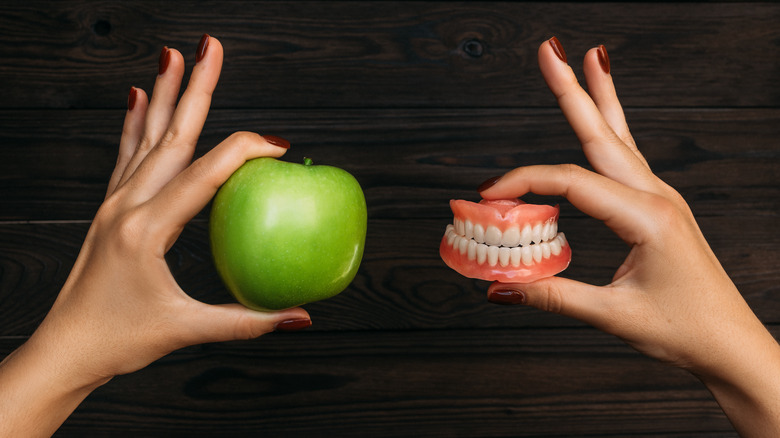 Hands holding apple and model teeth