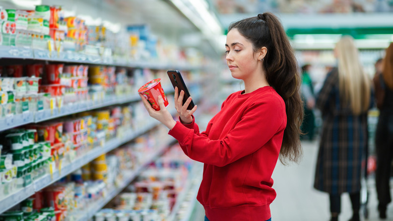 Woman in grocery store checking ingredients in yogurt