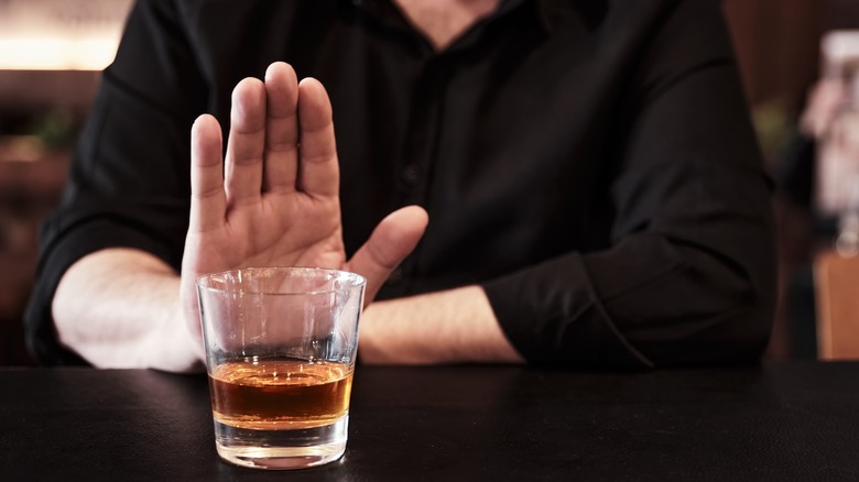 Man with lupus refusing a glass of alcohol