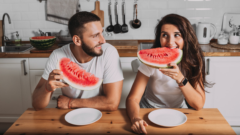 man and woman eating watermelon