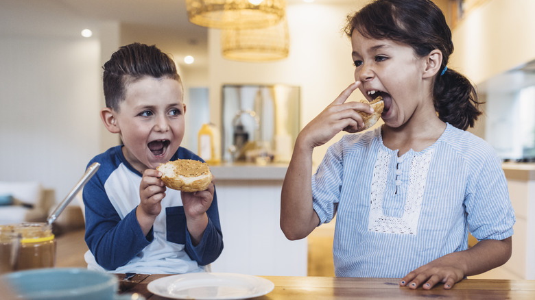 two children eating open peanut butter sandwiches