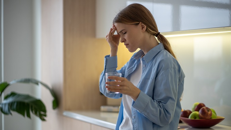 woman feeling dizzy holding a glass of water