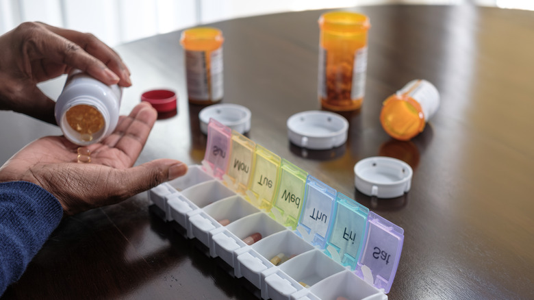 woman's hand organizing her pills in a pill case