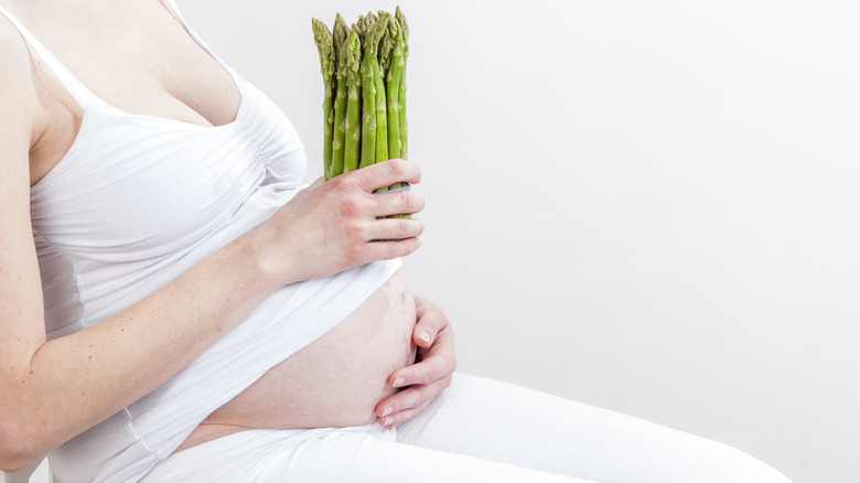 Pregnant woman holding asparagus