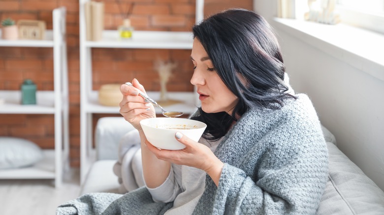 Woman eating soup while sick