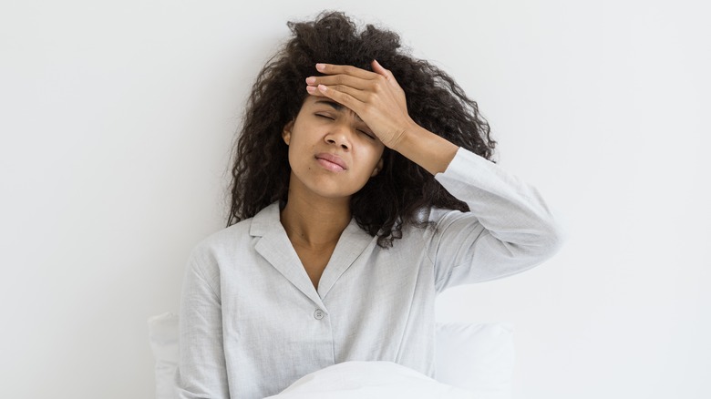 woman with a bad headache sitting in bed
