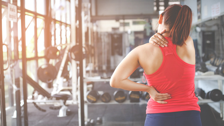 Woman in gym grasping neck