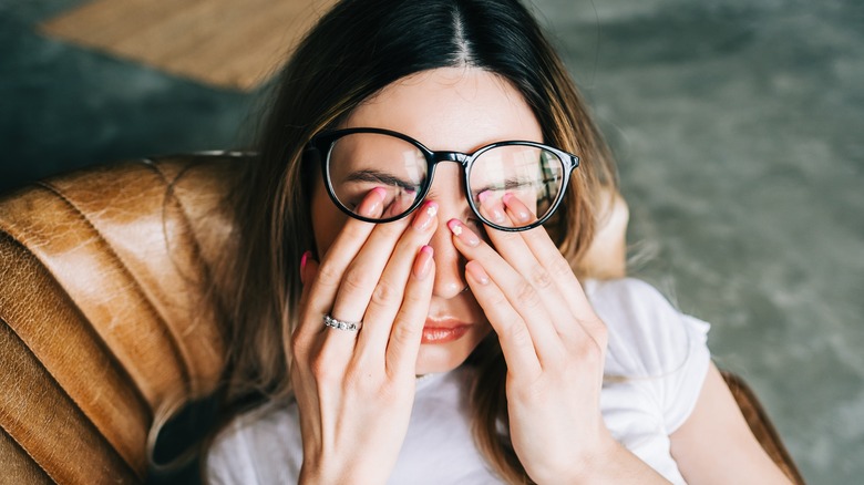 woman rub eyes under glasses