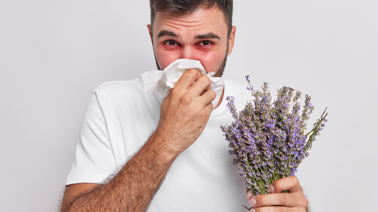 man holds flowers which trigger allergies