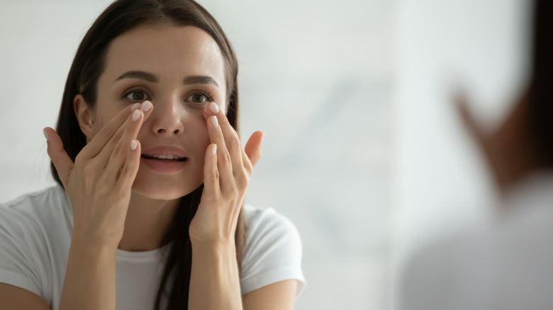 woman checking face in mirror