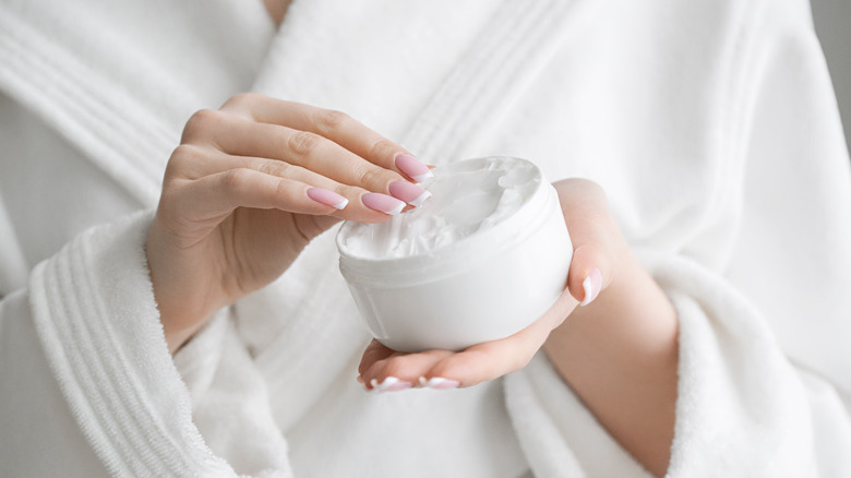 A woman is holding a jar of hand cream